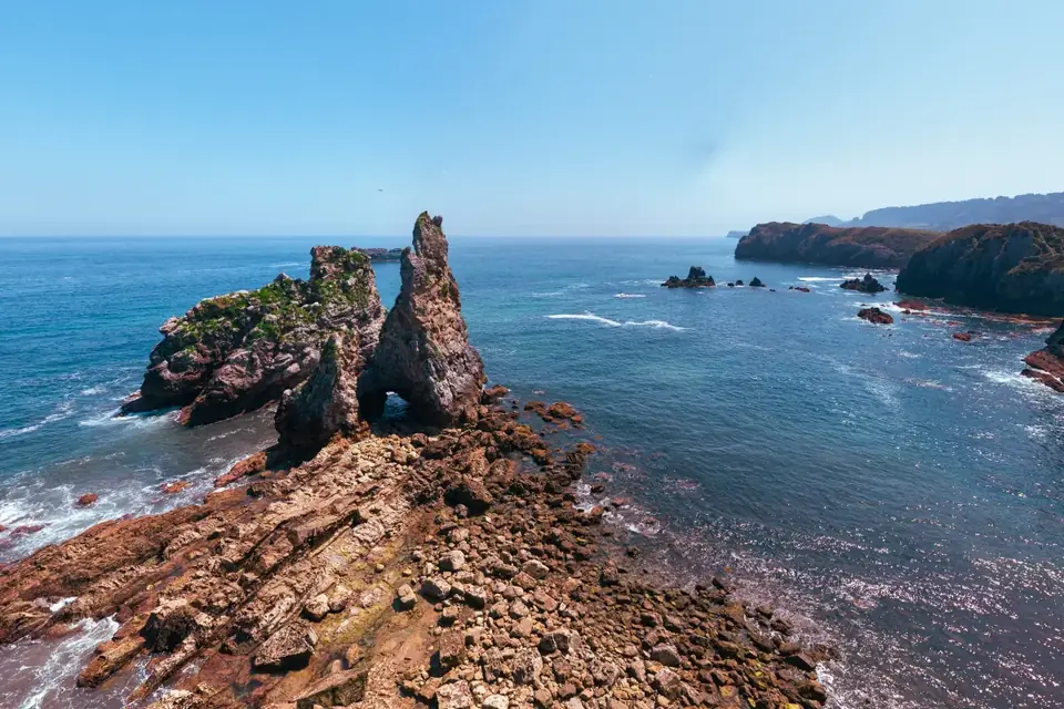 Playa de Pendueles, con el castro y su arco de roca frente a la arena