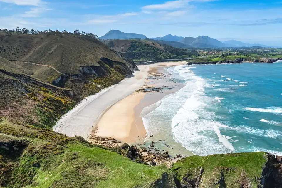 Playa de San Antolín de Bedón, el gran arenal abierto con las series de olas y la sierra detrás