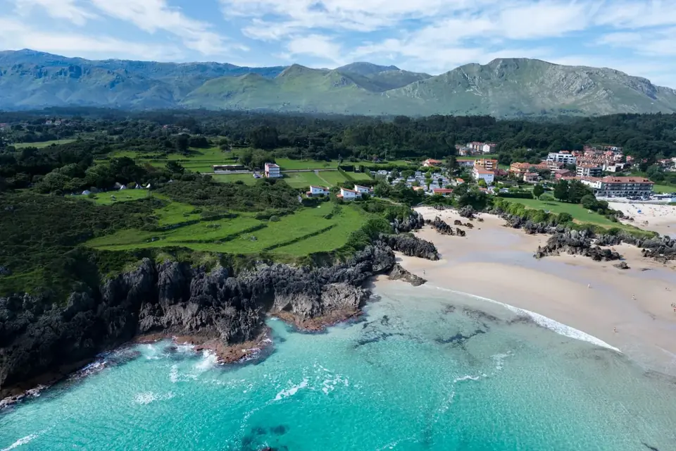 Arenales de agua turquesa al pie del pueblo de Barro, con la sierra del Cuera detrás