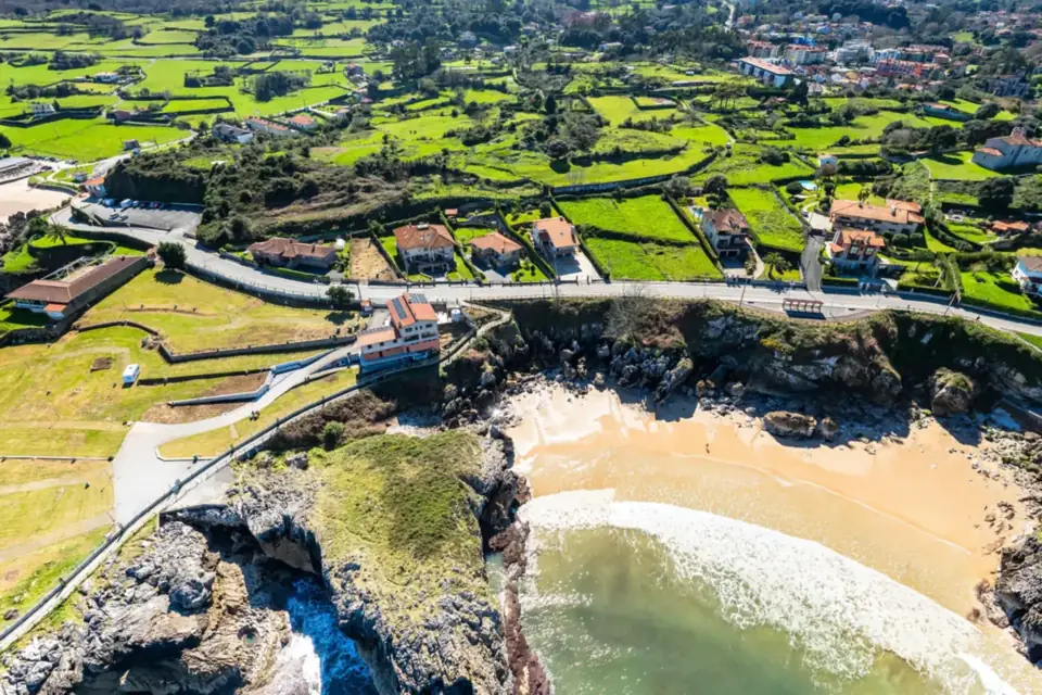 Playa de Puerto Chicu, la cala bajo las casas y los prados