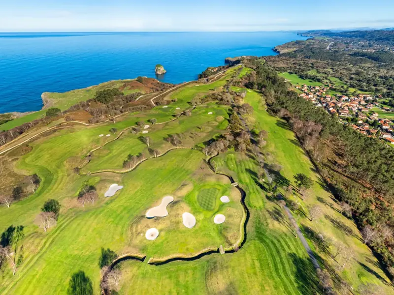 Vista aérea del Campo Municipal de Golf de Llanes sobre la rasa de Cue, con el Cantábrico al fondo